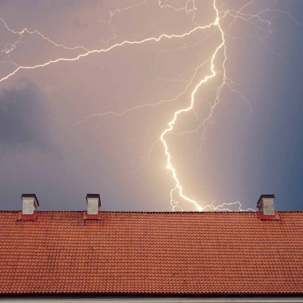 Nighttime thunderstorm with lightning bolt over rooftop in Dedham, MA