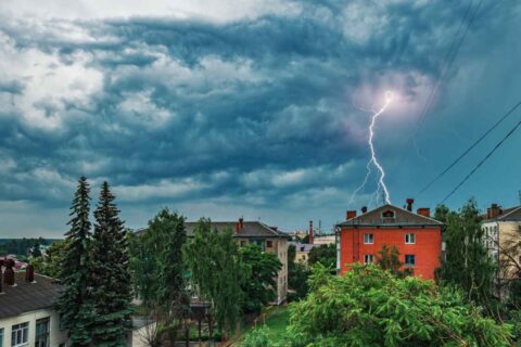 Powerful loop lightning arcs toward red building during storm in Dedham, MA