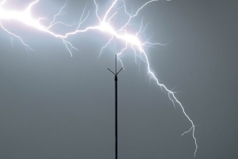 A lightning bolt strikes a pole, illustrating how lightning rods attract lightning in Dedham, MA